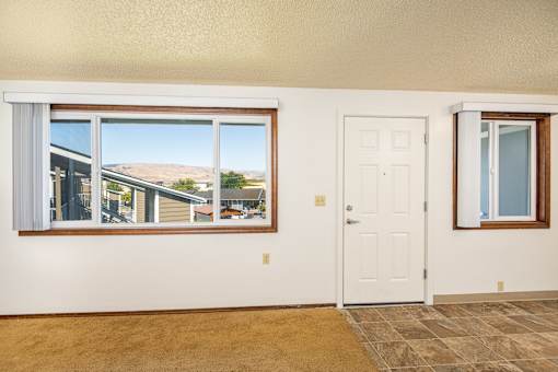 A room with a white door and a window overlooking a residential area.