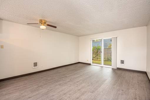 an empty living room with wood floors and a ceiling fan