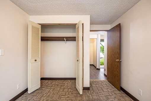 an empty room with a closet and a door to a hallway