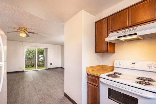 an empty kitchen with a stove and a ceiling fan