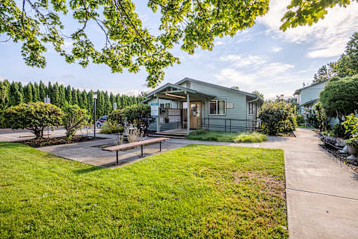 a green house with a sidewalk and a picnic table