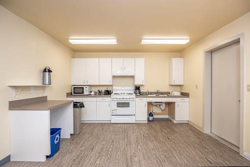 A kitchen with white cabinets and a wooden floor.