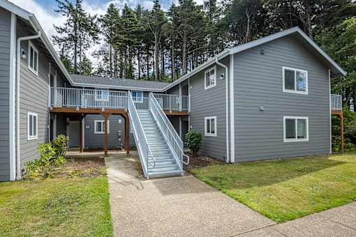 A grey house with a staircase leading to the second floor.
