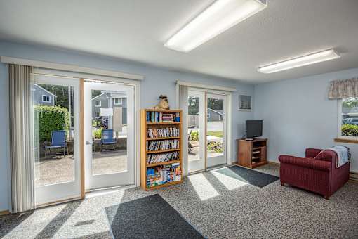 A living room with a red chair and a bookshelf filled with books.