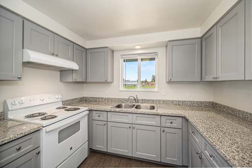 A kitchen with a white stove top oven and a window.