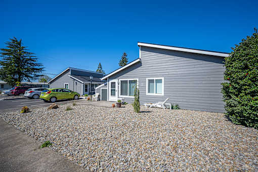 A grey house with a gravel driveway in front.
