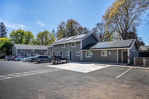 A parking lot in front of a building with solar panels on the roof.