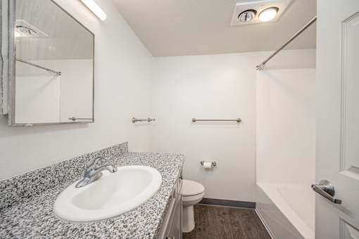 A bathroom with a granite countertop and a white sink.