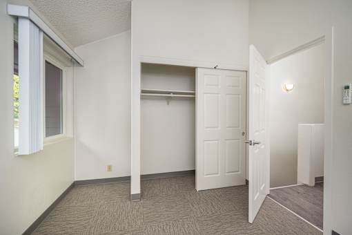 A room with a white door, a window with white curtains, and a small white cabinet.