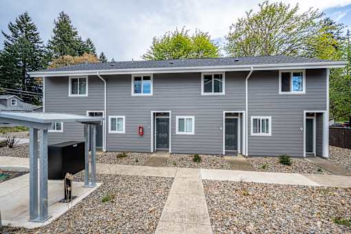 A grey house with a red fire extinguisher on the wall.