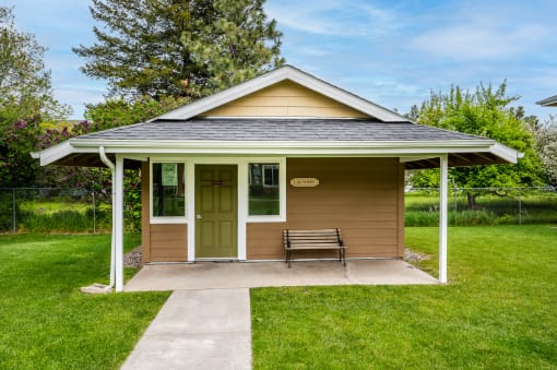 a small brown building with a bench in front of it