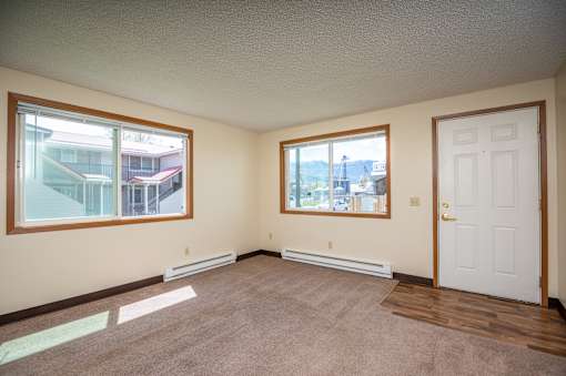 an empty living room with two windows and a door