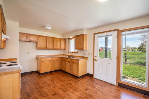 a kitchen with wooden cabinets and a door leading out to a yard