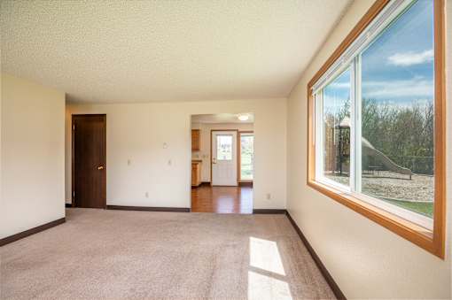 a living room with a large window and a carpeted floor