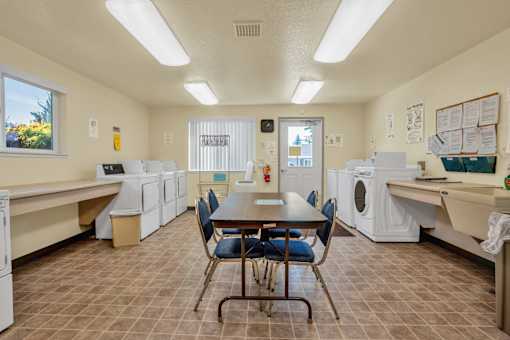 a laundry room with a table and chairs and washing machines