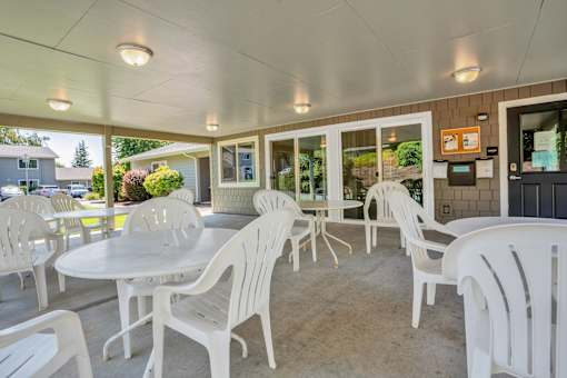 a patio with white chairs and tables and windows
