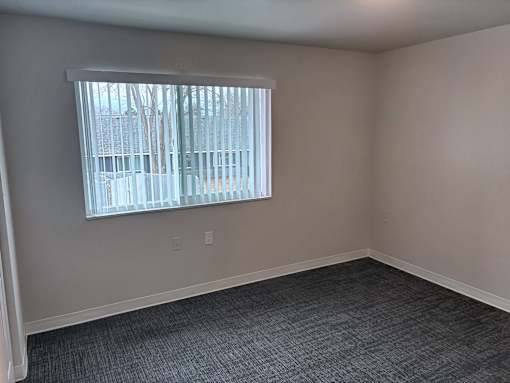 A room with a window covered by a white blind.
