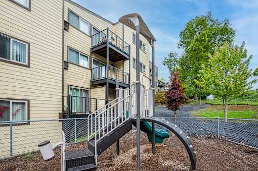 A playground with a slide is in front of a building.