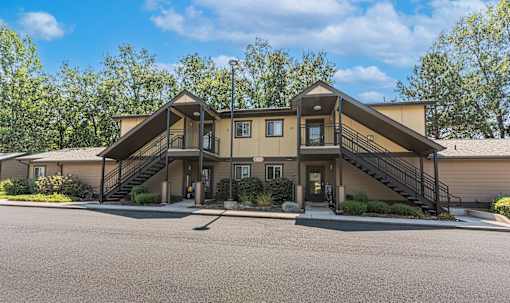 the front of a house with stairs and a parking lot