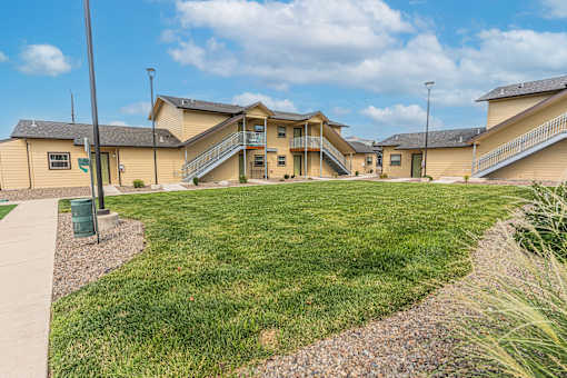 A grassy area in front of a building with a gravel path.