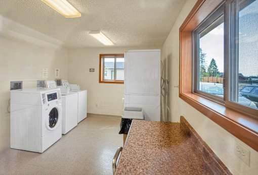 A laundry room with a washer and dryer, a window, and a counter.