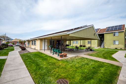 A green and yellow house with a patio and solar panels on the roof.