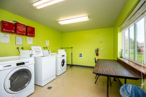 A laundry room with a washer and dryer, a table, and a window.