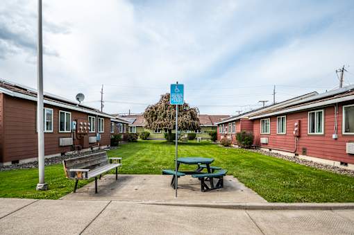 A blue sign is in the distance behind a green picnic table.