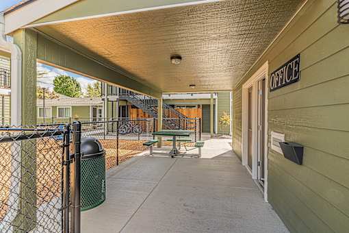 a covered patio with a picnic table and a chain link fence