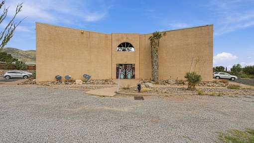A tan building with a large arched doorway and a small window above it.