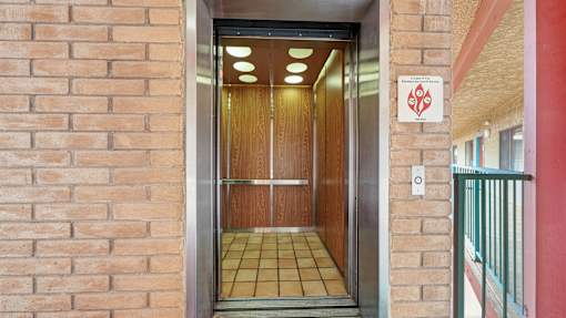 A red sign with a white symbol is on a brick wall above a door.