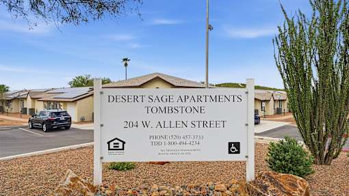 A sign for Desert Sage Apartments in Tombstone stands in front of the building.