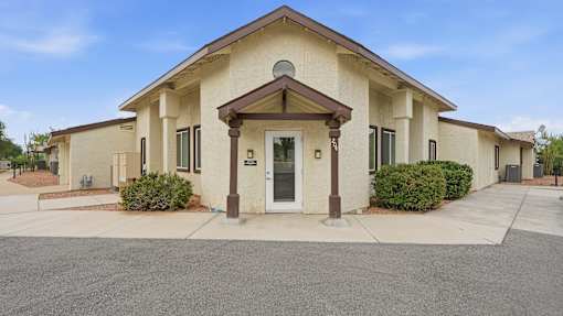 A building with a brown roof and beige walls with a white door and windows.