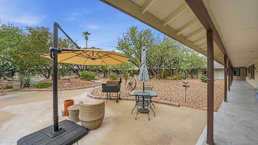 A patio with a table and chairs under a yellow umbrella.