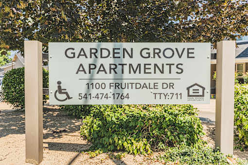 a garden grove apartments sign in front of a tree