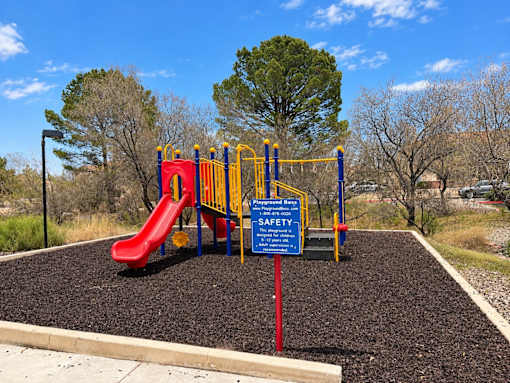 A playground with a red slide and a blue safety sign.