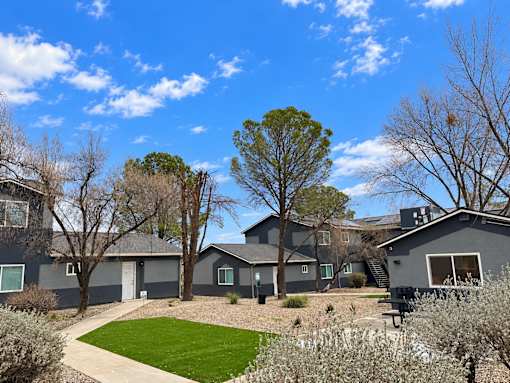 A grey house with a green lawn and trees.