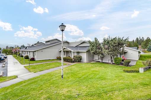 the view of a gray house with a yard and street light