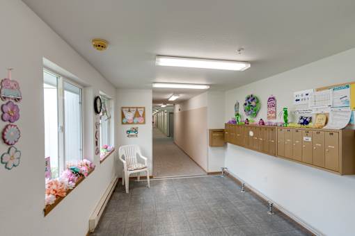 a hallway with a white chair and a window and a white wall with a counter