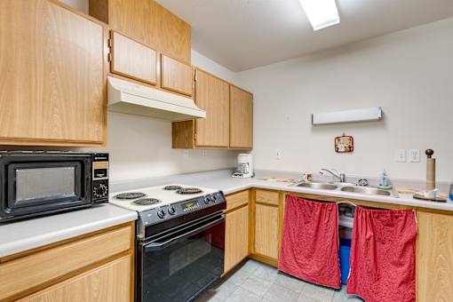 a kitchen with wooden cabinets and a stove microwave and sink