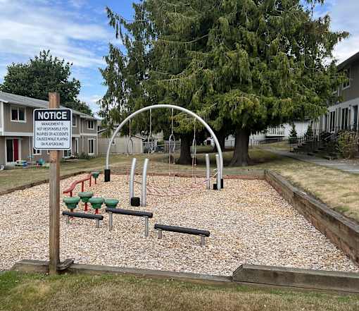 A playground with a notice sign in front of a building.