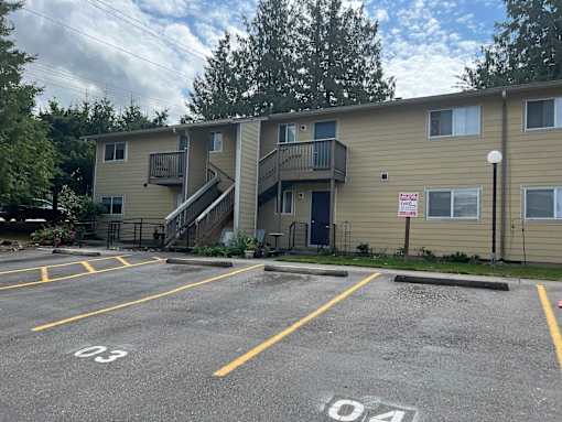 Apartment complex with a parking lot in front.