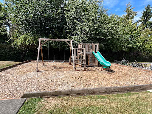 A playground with a green slide and a wooden structure.