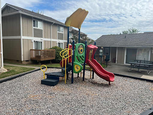 A playground with a red slide and a yellow and green climbing structure.