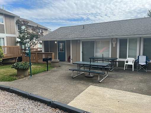 A patio with a table and chairs is in front of a house.