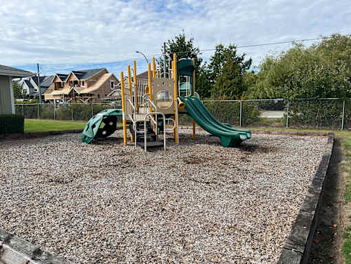A playground with a green slide and yellow structure.