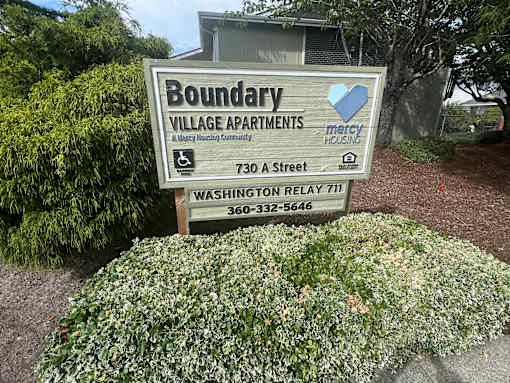A sign for Boundary Village Apartments is displayed in front of a building.