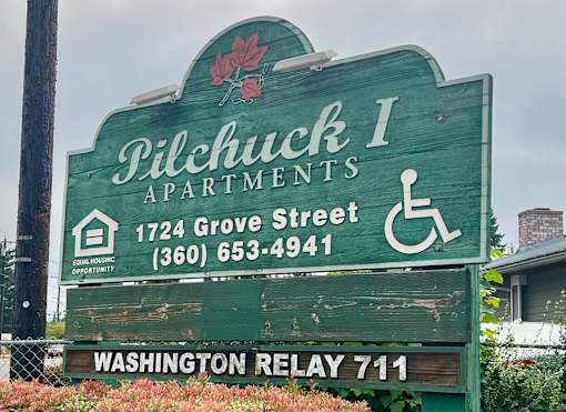 A sign for Pilchuck I Apartments with a wheelchair symbol indicating accessibility.