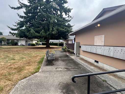 A concrete walkway leads to a building with a row of mailboxes on the side.