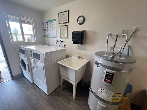 A laundry room with a washer and dryer, a sink, and a detergent dispenser.